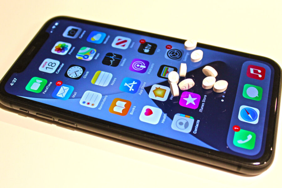 A smartphone will prescription drugs sitting on top of the screen